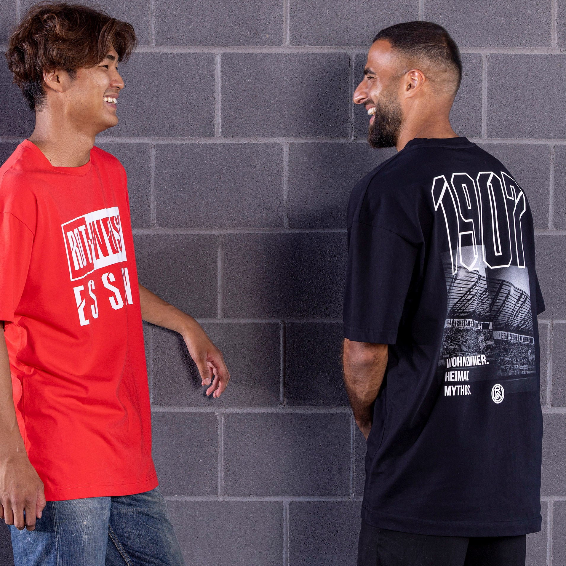 Ramien Safi trägt schwarzes Oversize T-Shirt mit großem Rückenprint; vorne schlicht mit Koordinaten des Stadions auf der linken Brust