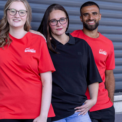 Jasmin trägt schwarzes oversize Polo mit V-Ausschnitt und "RWE" Stickerei in schwarz auf linker Brust, keine Knopfleiste