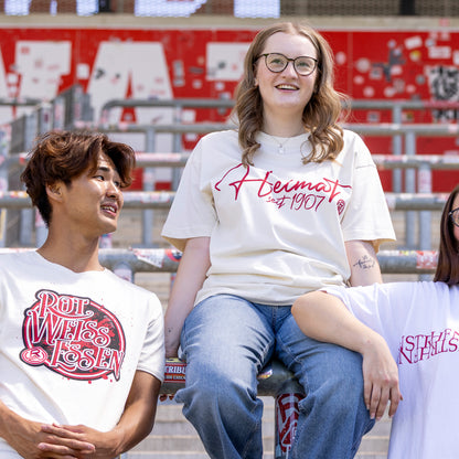 Marie trägt cremefarbenes Oversize T-Shirt mit einem roten "Heimat seit 1907"-Druck mittig auf der Brust, inkl. Rot-Weiss Essen Logo