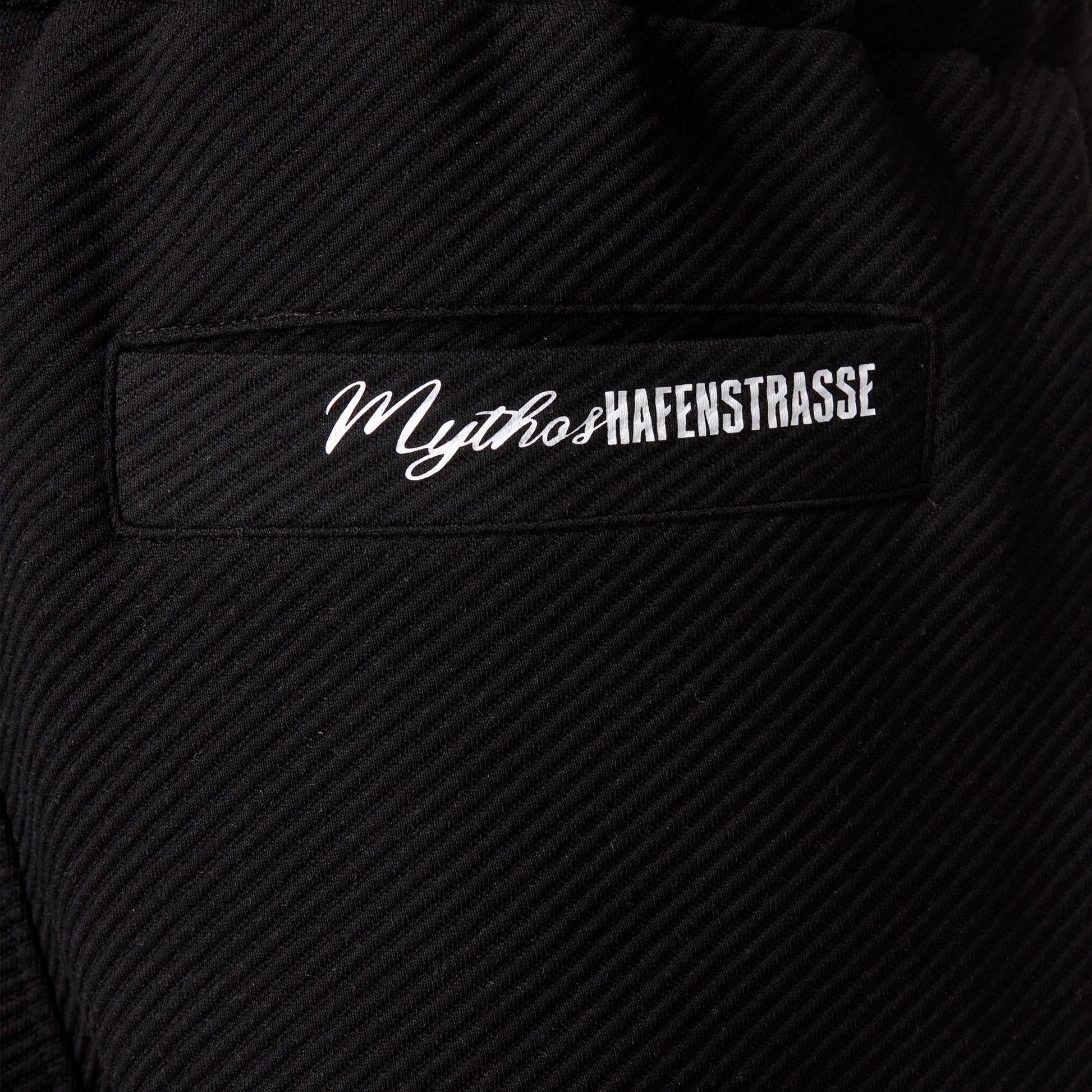 Nahaufnahme Style 2559 Hose "Mythos" Druck, "Mythos" vorne in kursiver Schrift, danach "HAFENSTRASSE" in RWE-Blockschrift, beides aneinandergereiht