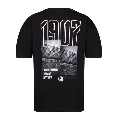 Schwarzes Oversize T-Shirt mit großem Rückenprint; abgebildet sind die West-Tribüne mit "1907" Schriftzug, sowie dem Slogan "Wohnzimmer. Heimat. Mythos" und dem RWE-Logo.